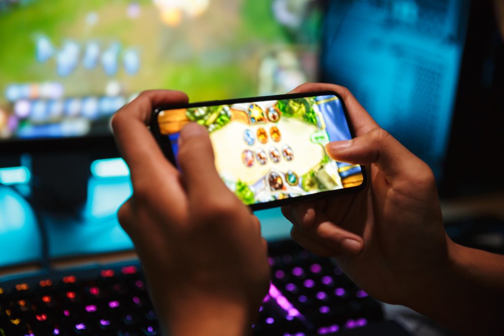 Pessoa jogando videogame online em um smartphone, mostrando uma interface de jogo mobile com gráficos coloridos