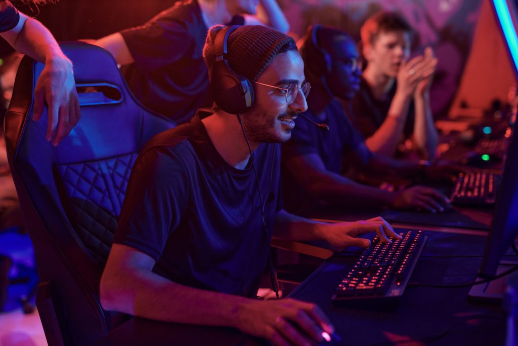 Jogadores de e-sports usando fones de ouvido competindo em PCs em um setup de e-sports com iluminação neon