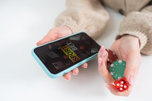 Pessoa segurando um smartphone com tela de apostas esportivas e fichas de cassino para jogos online no Brasil.