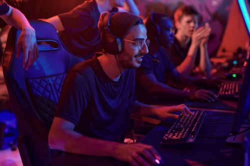 Jogadores de e-sports usando fones de ouvido competindo em PCs em um setup de e-sports com iluminação neon